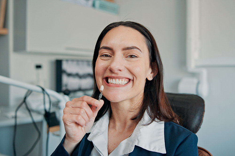 Woman holding a dental implant next to her teeth